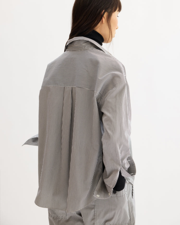 A person with long brown hair, seen from behind, wears the Arlo Mott Watts Side Button Shirt in White Stripe over a black top, paired with matching pants for a relaxed look.