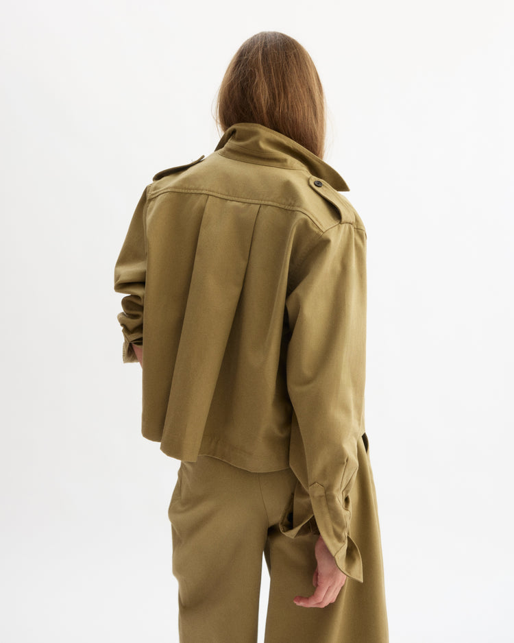 Seen from behind against a plain white background, a person with long brown hair wears the Arlo Mott Henry Short Shirt Jacket in Khaki with matching pants.