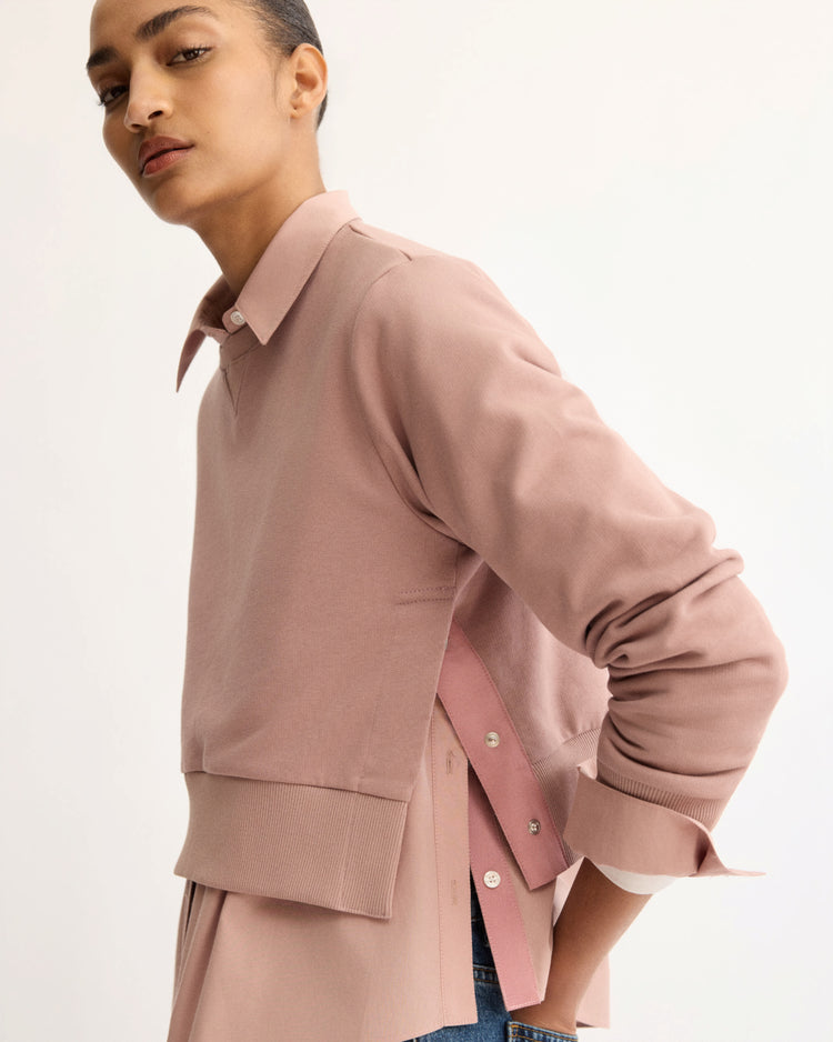 A person with tied-back hair models the Arlo Mott Kent Crewneck With Snaps in Dusty Rose, facing sideways against a plain light background.