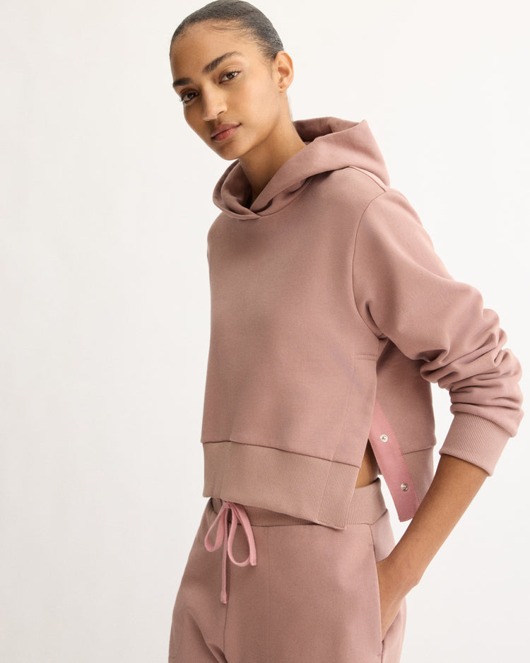 A woman models the Arlo Mott Morris Hoodie With Snaps in Dusty Rose, standing against a plain light background and looking at the camera.