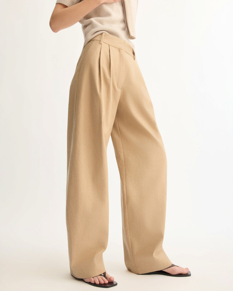 A person models the Arlo Mott Horatio Pleated Barrel Trouser in Khaki—high-rise, wide-leg Japanese twill pants with pleats—paired with a light short-sleeve top and black thong sandals against a white background. The face is not shown.