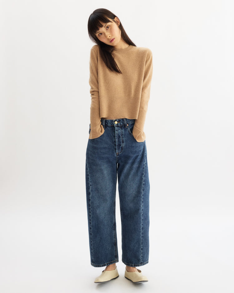 A woman with her hands in her pockets, wearing the Arlo Mott Warren Classic Crew Neck in Honey, crafted from luxurious Italian cashmere.