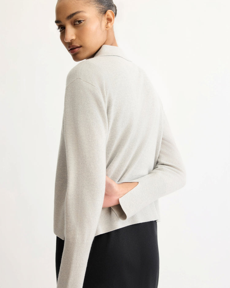 A person with pulled-back hair wears the Arlo Mott Berry Polo Long Sleeve in Grey and black bottoms, standing sideways and looking over their shoulder against a plain light background.
