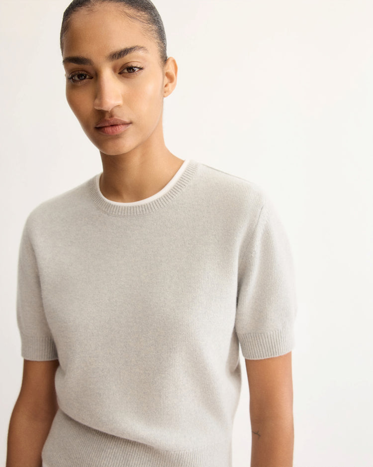 A person with neatly pulled-back hair wears the Arlo Mott Clarkson Short Sleeve Crewneck in Grey, standing against a plain light background and calmly looking at the camera.