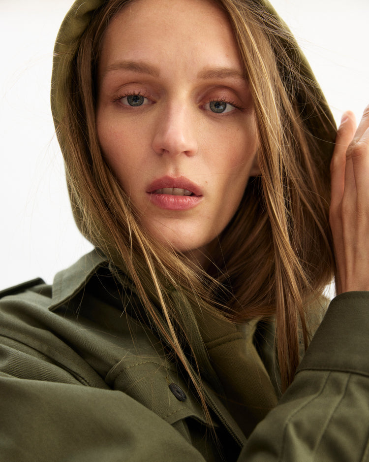Woman wearing a green jacket with a neutral background